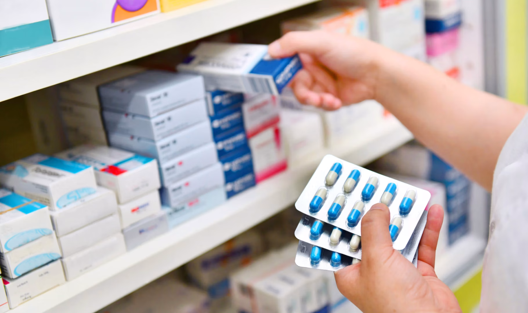 Pharmacist holding medicine box and capsule pack in pharmacy dru