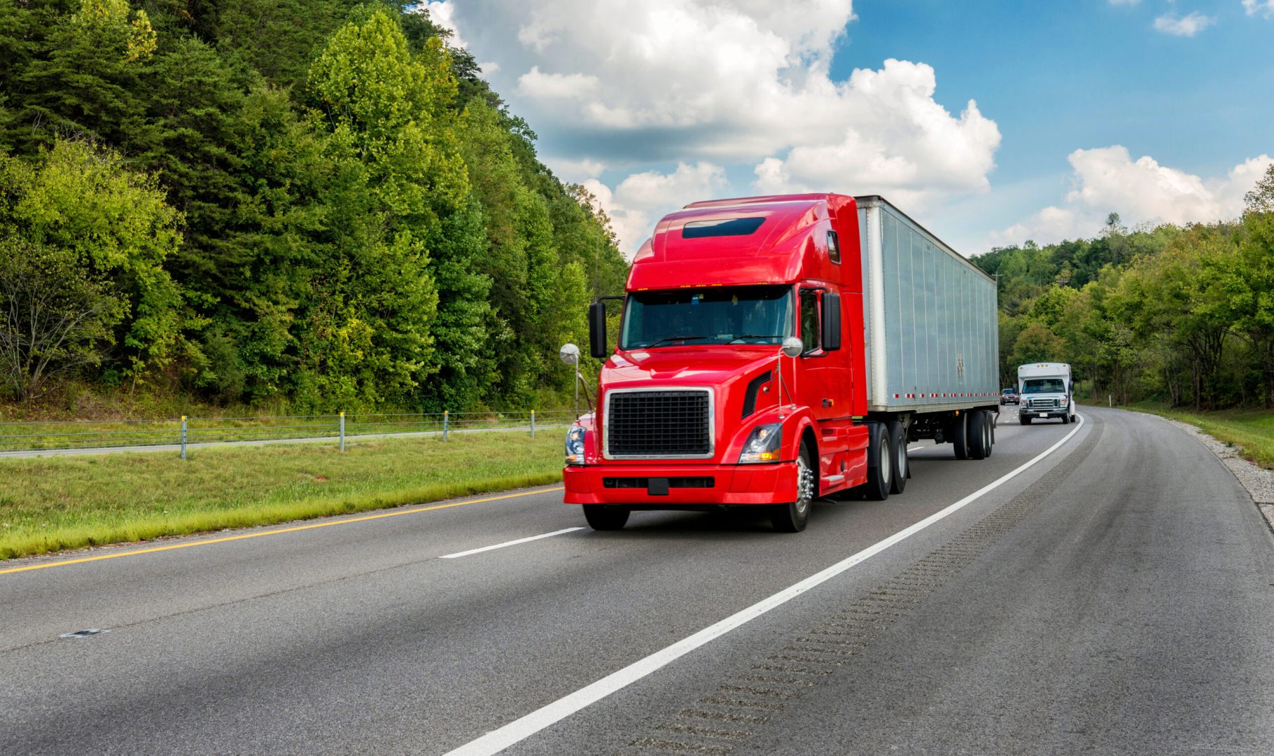 Horizontal shot of a red semi truck going down an interstate highway.